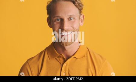 Joli homme joyeux et gai à la barbe, qui regarde avec joie dans l'appareil photo sur des couleurs vives arrière-plan Banque D'Images