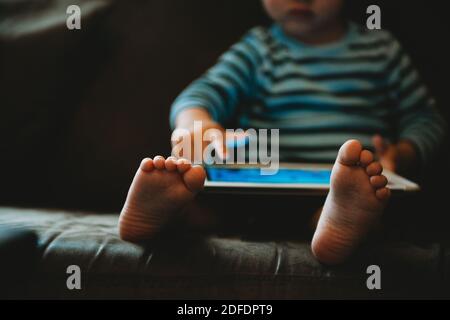 Jeune enfant jouant avec une tablette pendant l'isolement en quarantaine Banque D'Images