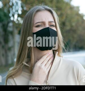 Femme avec un masque de protection ayant un mal de gorge Banque D'Images