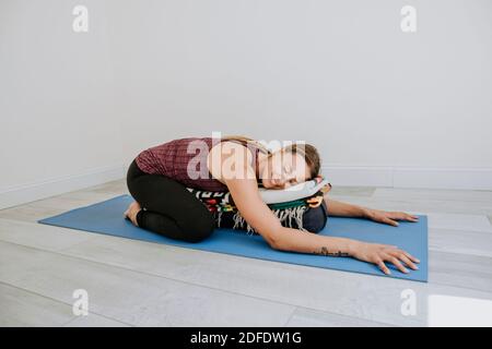 FIT athlétique femme étire son dos sur bleu tapis de yoga, Portland, MOI Banque D'Images