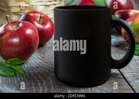 Tasse à café noire avec pommes rouges. Vider la maquette de tasse pour la présentation des produits. Maquette de tasse à café. Banque D'Images