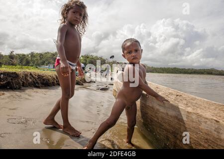 Jeunes enfants pauvres jouant à côté d'un canot en bois près de la rivière Platano. Barra Platano, Mosquitia, Honduras Banque D'Images