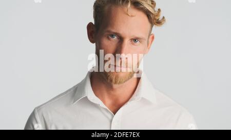 Jeune homme d'affaires beau barbu en chemise regardant avec assurance dans l'appareil photo isolé sur fond blanc Banque D'Images