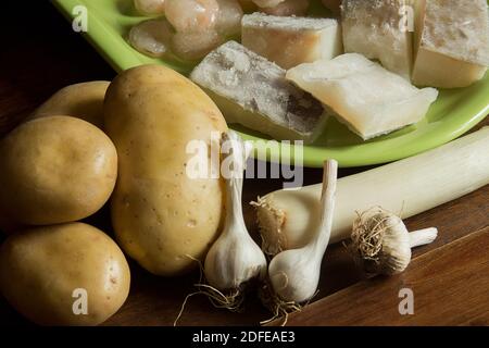 Produits biologiques de jardin avec des loins de morue. Un groupe de pommes de terre, de poireaux, d'ail et de poissons sur une table en bois. Banque D'Images