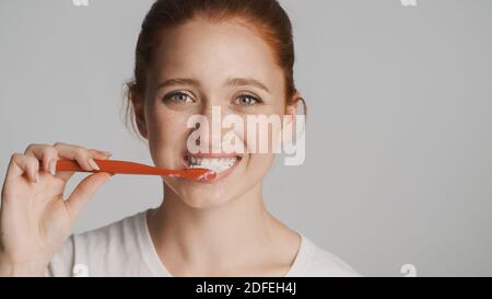 Portrait de belle fille heureusement se brosser les dents regardant dans l'appareil photo sur fond blanc Banque D'Images