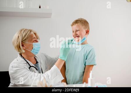 Femme médecin effectuant un test de bouche-écouvillon sur un peu enfant Banque D'Images