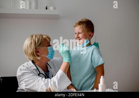 Femme médecin effectuant un test de bouche-écouvillon sur un peu enfant Banque D'Images