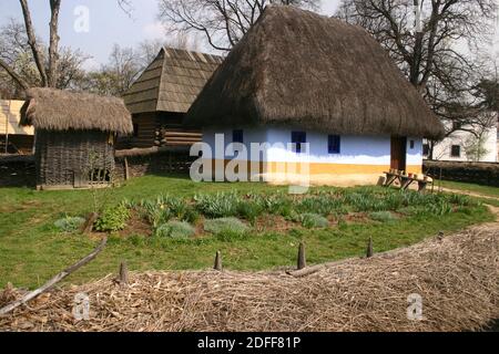 Musée du village, Bucarest, Roumanie. Authentique maison du XIXe siècle du comté d'Alba, avec toit de chaume. Clôture en paille et abri à maïs. Banque D'Images