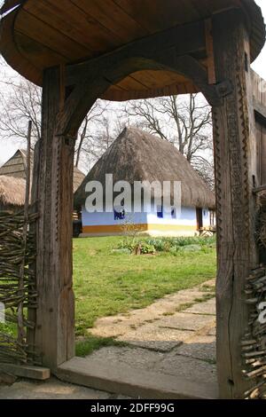 Musée du village, Bucarest, Roumanie. Authentique maison du XIXe siècle du comté d'Alba, avec toit de chaume. Portail en bois sculpté traditionnel. Banque D'Images