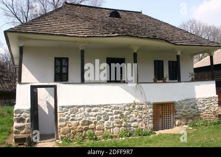 Musée du village, Bucarest, Roumanie. Maison en bois du XIXe siècle du comté d'Arges, avec toit en bardeaux en bois, balcon, fondation en pierre et cave. Banque D'Images