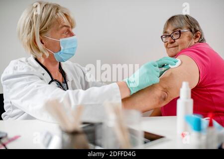 La femme médecin fait la vaccination à la femme. Ils portent un masque facial de protection. Banque D'Images
