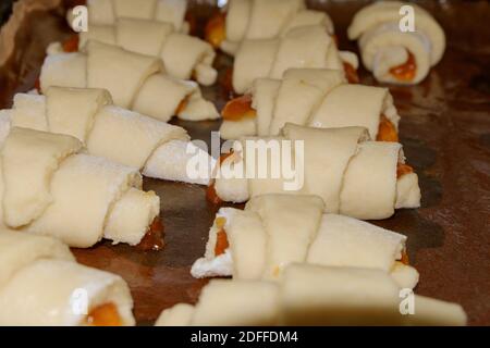 Biscuits faits maison roulés dans un tube avec remplissage de confiture sur une plaque de cuisson avec un dos de papier humidifié avec de l'huile végétale. Mise au point sélective. Banque D'Images