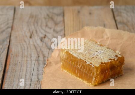 Miel en nid d'abeille sur papier d'emballage sur une table en bois. Mise au point sélective. Banque D'Images