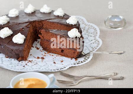 Délicieux gâteau viennois au cacao avec confiture de cassis et recouvert de chocolat noir et de crème, servi avec du café Banque D'Images