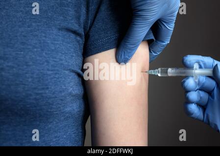 Injection du vaccin COVID-19, le médecin en gants tient la seringue et fait du jab à la patiente en clinique. Prévention du coronavirus ou de la grippe. Concept o Banque D'Images