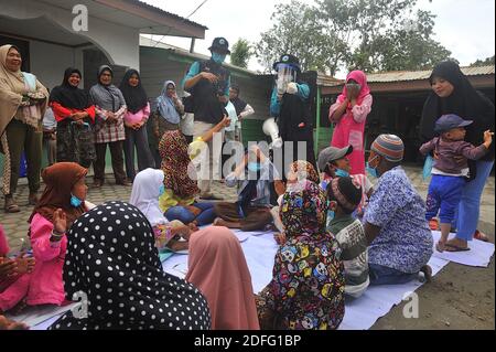 Une femme volontaire vue a donné des points d'esprit pour les enfants qui ont touché par l'éruption du volcan Sinabung pendant a reçu l'aide des volontaires de la Fondation Al Kahfi comme une action d'aide caritative pour les résidents des villages de Kuta Tengah, Berastepu et Gamber (Tiga Serangkai) À la mosquée Al-Jihad à Karo, dans le nord de Sumatra, en Indonésie, le 30 août 2020. Dans plusieurs nouvelles liées à l'éruption du volcan Sinabung, humanely quelques volontaires d'Al-Kahfi sont venus à la psychologie traitée des résidents, en particulier pour les enfants qui vivent sur le seuil d'une zone de danger de catastrophe géologique. Photo par Banque D'Images