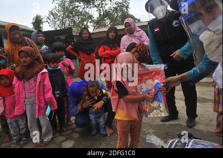 Une femme volontaire vue a donné des points d'esprit pour les enfants qui ont touché par l'éruption du volcan Sinabung pendant a reçu l'aide des volontaires de la Fondation Al Kahfi comme une action d'aide caritative pour les résidents des villages de Kuta Tengah, Berastepu et Gamber (Tiga Serangkai) À la mosquée Al-Jihad à Karo, dans le nord de Sumatra, en Indonésie, le 30 août 2020. Dans plusieurs nouvelles liées à l'éruption du volcan Sinabung, humanely quelques volontaires d'Al-Kahfi sont venus à la psychologie traitée des résidents, en particulier pour les enfants qui vivent sur le seuil d'une zone de danger de catastrophe géologique. Photo par Banque D'Images