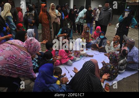 Une femme volontaire vue a donné des points d'esprit pour les enfants qui ont touché par l'éruption du volcan Sinabung pendant a reçu l'aide des volontaires de la Fondation Al Kahfi comme une action d'aide caritative pour les résidents des villages de Kuta Tengah, Berastepu et Gamber (Tiga Serangkai) À la mosquée Al-Jihad à Karo, dans le nord de Sumatra, en Indonésie, le 30 août 2020. Dans plusieurs nouvelles liées à l'éruption du volcan Sinabung, humanely quelques volontaires d'Al-Kahfi sont venus à la psychologie traitée des résidents, en particulier pour les enfants qui vivent sur le seuil d'une zone de danger de catastrophe géologique. Photo par Banque D'Images