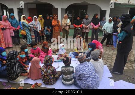 Une femme volontaire vue a donné des points d'esprit pour les enfants qui ont touché par l'éruption du volcan Sinabung pendant a reçu l'aide des volontaires de la Fondation Al Kahfi comme une action d'aide caritative pour les résidents des villages de Kuta Tengah, Berastepu et Gamber (Tiga Serangkai) À la mosquée Al-Jihad à Karo, dans le nord de Sumatra, en Indonésie, le 30 août 2020. Dans plusieurs nouvelles liées à l'éruption du volcan Sinabung, humanely quelques volontaires d'Al-Kahfi sont venus à la psychologie traitée des résidents, en particulier pour les enfants qui vivent sur le seuil d'une zone de danger de catastrophe géologique. Photo par Banque D'Images