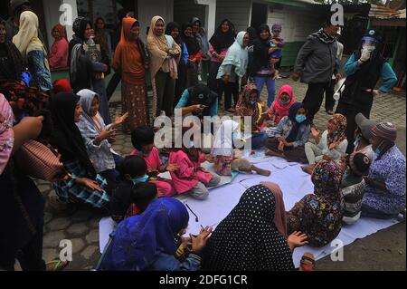 Une femme volontaire vue a donné des points d'esprit pour les enfants qui ont touché par l'éruption du volcan Sinabung pendant a reçu l'aide des volontaires de la Fondation Al Kahfi comme une action d'aide caritative pour les résidents des villages de Kuta Tengah, Berastepu et Gamber (Tiga Serangkai) À la mosquée Al-Jihad à Karo, dans le nord de Sumatra, en Indonésie, le 30 août 2020. Dans plusieurs nouvelles liées à l'éruption du volcan Sinabung, humanely quelques volontaires d'Al-Kahfi sont venus à la psychologie traitée des résidents, en particulier pour les enfants qui vivent sur le seuil d'une zone de danger de catastrophe géologique. Photo par Banque D'Images