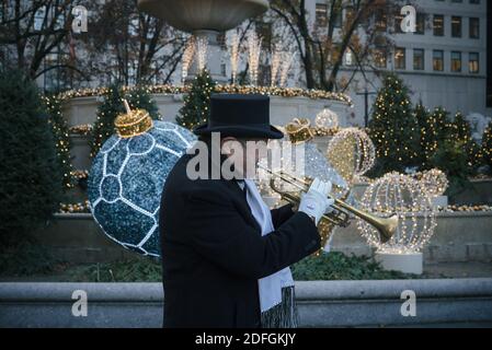 New York. 03 décembre 2020. Le musicien de rue Jacques Letalon interprète des chants de Noël devant la fontaine Pulitzer décorée du Grand Army Plaza. Banque D'Images
