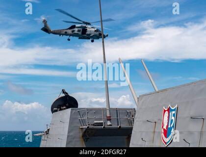 Remettre une photo de dossier datée du 18 août 2020 un hélicoptère MH-60R affecté à l'Escadron de frappe maritime (UGV) 51 prend son départ du pont de vol, alors que le destroyer à missiles guidés de la classe Arleigh Burke USS Mustin (DDG 89) effectue des opérations de routine. Un navire de guerre de la Marine américaine a transité pour la deuxième fois en deux semaines dans le détroit de Taiwan, un détroit étroit et sensible. Le ministère de la Défense de Taïwan a confirmé l'opération lundi dans un contexte de tensions croissantes entre la Chine et les États-Unis. Le ministère a dit qu'un destroyer américain, qu'il n'a pas nommé, avait navigué dans une direction sud à travers le détroit et était c Banque D'Images