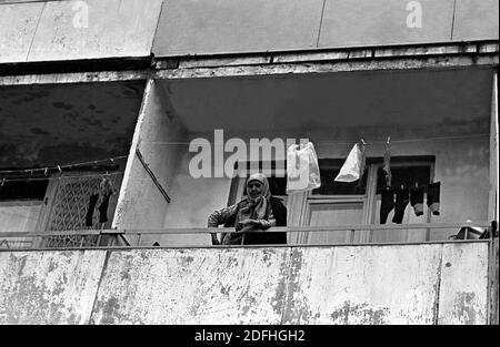 Photo en noir et blanc d'une vieille femme debout sur le balcon d'une maison de panneaux à plusieurs étages, URSS Banque D'Images