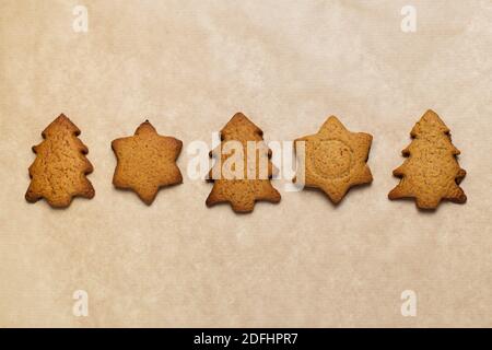 Petits gâteaux de noël en pain d'épice sur un papier de pâtisserie gros plan. Banque D'Images