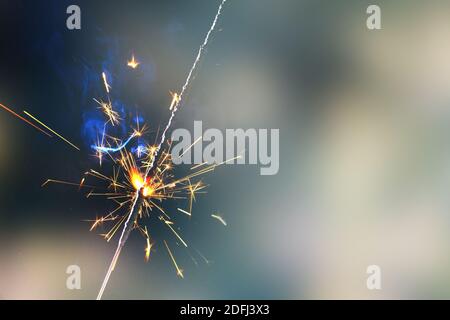 Bonne année de feu de sparkler dans la main femelle sur fond de sapin de noël avec lumières Banque D'Images