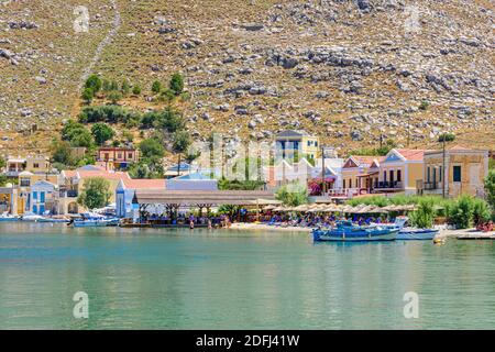 Taverne en bord de mer et parasols de plage à Pedi Bay, Symi Island, Dodécanèse, Grèce Banque D'Images