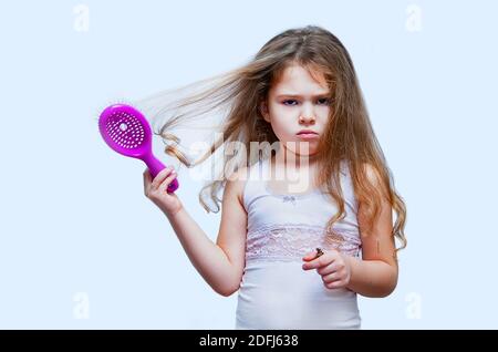 Concept de soins de cheveux avec le portrait de la fille se brossant ses cheveux longs indisciplinés, emmêlés Banque D'Images
