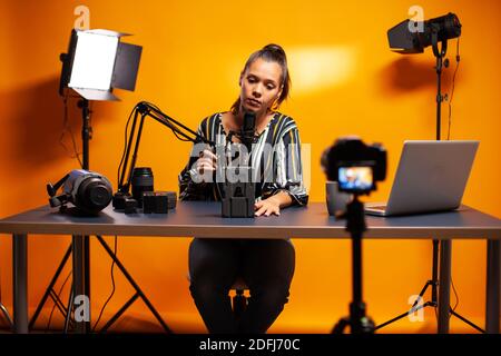 Tenir le microphone et parler de la batterie pour la caméra professionnelle de vidéaste. Revue professionnelle des équipements de vidéographie par le créateur de contenu, nouvelle star des médias influenceur sur les médias sociaux. Banque D'Images