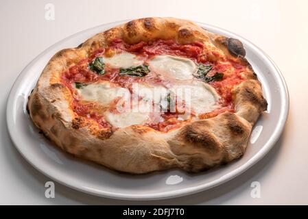 Pizza de Naples, Italie, appelée margherita parce qu'il est dédié à la reine - pizza avec bord croustillant, tomate, mozzarella et basilic dans la plaque blanche Banque D'Images