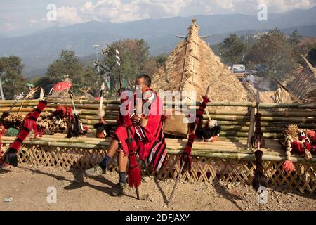 Un ancien guerrier naga vêtu d'une tenue traditionnelle avec Armes traditionnelles conservées à ses côtés dans le village kisama Nagaland Inde 2 décembre 2016 Banque D'Images