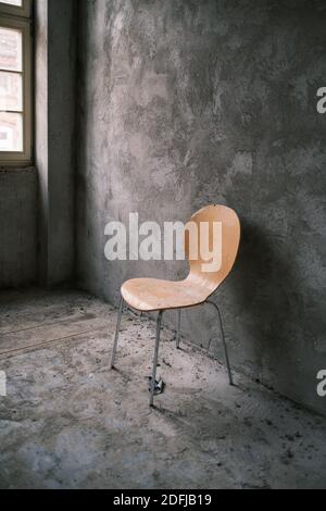 devant un support mural gris fraîchement plâtré une chaise jaune Banque D'Images