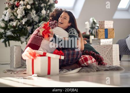 Un jeune couple dans un câlin assis sur le sol heureux à Noël sur un beau matin de vacances. Noël, relation, amour, ensemble Banque D'Images