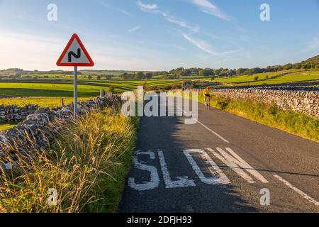 Vue sur les murs en pierre sèche et le cycliste sur la Country Lane, Foolow, Derbyshire Peak District, Angleterre, Royaume-Uni, Europe Banque D'Images