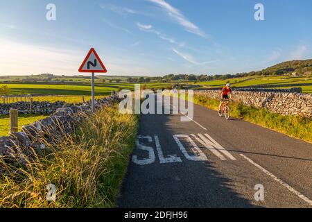 Vue sur les murs en pierre sèche et le cycliste sur la Country Lane, Foolow, Derbyshire Peak District, Angleterre, Royaume-Uni, Europe Banque D'Images