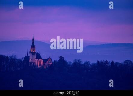 05 décembre 2020, Hessen, Rüdesheim: La chapelle Saint-Rochus sur le Rochusberg en Rhénanie-Palatinat est illuminée par des projecteurs dans la dernière lumière du jour alors que le soleil se couche derrière un épais groupe de nuages. Dans les prochains jours, le temps devrait rester nuageux et couvert dans de grandes parties de l'Allemagne. Photo : Boris Roessler/dpa Banque D'Images