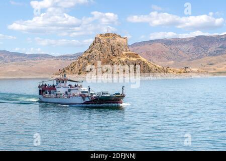 Pertek, Tunceli, Turquie-septembre 18 2020 : le ferry qui relie les villes d'Elazig et de Tunceli et la forteresse de Pertek en arrière-plan Banque D'Images