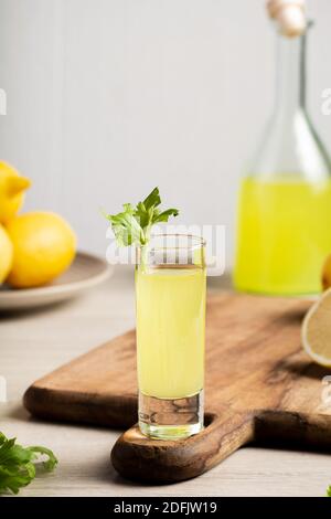 Liqueur italienne traditionnelle Limoncello. Bouteille en verre avec liqueur de Limoncello maison, assiette avec citrons et céleri. Banque D'Images