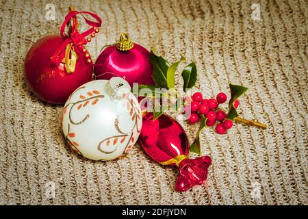 Boules de Noël rouges et dorées. Une branche de houx pour la saison des fêtes. Banque D'Images