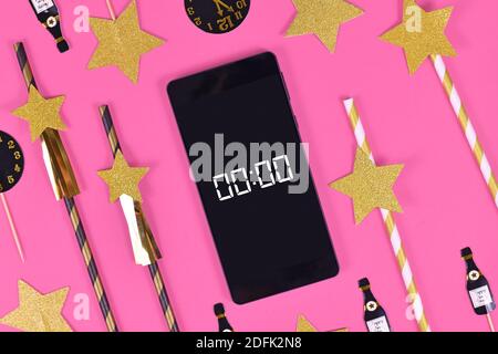 Nouveau Silvester célébration concept avec smartphone avec minuterie compte à rebours jusqu'à minuit entre les articles de fête comme les pailles en papier et papier champaign bot Banque D'Images