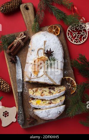 Noël savoureux stollen avec des fruits secs, des baies et des noix sur fond rouge. Gâteries traditionnelles allemandes. Format vertical. Vue de dessus Banque D'Images