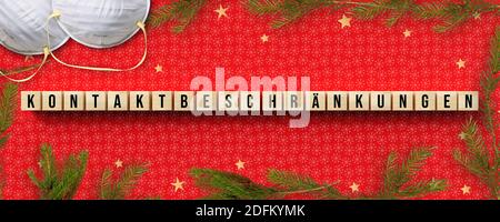 Cubes avec LIMITES de CONTACT de message allemand en plus des masques faciaux et décoration de noël sur fond rouge Banque D'Images