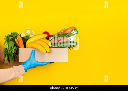 Livraison de nourriture sûre, achats en ligne ou concept de don. Livraison de nourriture pendant la quarantaine du coronavirus. Boîte avec différents ingrédients alimentaires dans ha femelle Banque D'Images