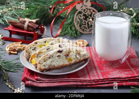 Tranche de Noël savoureux stollen avec des fruits secs et un verre de lait. Offrez-vous un cadeau pour le Père Noël. Gâteries traditionnelles allemandes. Gros plan Banque D'Images