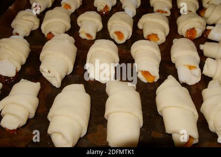 Biscuits faits maison roulés dans un tube avec remplissage de confiture sur une plaque de cuisson avec un dos de papier humidifié avec de l'huile végétale. Mise au point sélective. Banque D'Images