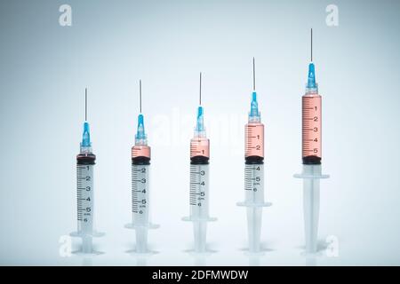 Seringues seringues à usage unique, en plastique, avec aiguilles hypodermiques fixées. La quantité de liquide coloré augmente dans les seringues consécutives. CAN Banque D'Images
