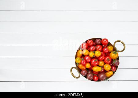 Tomates colorées en passoire sur une table en bois blanc. Vue de dessus, espace de copie Banque D'Images